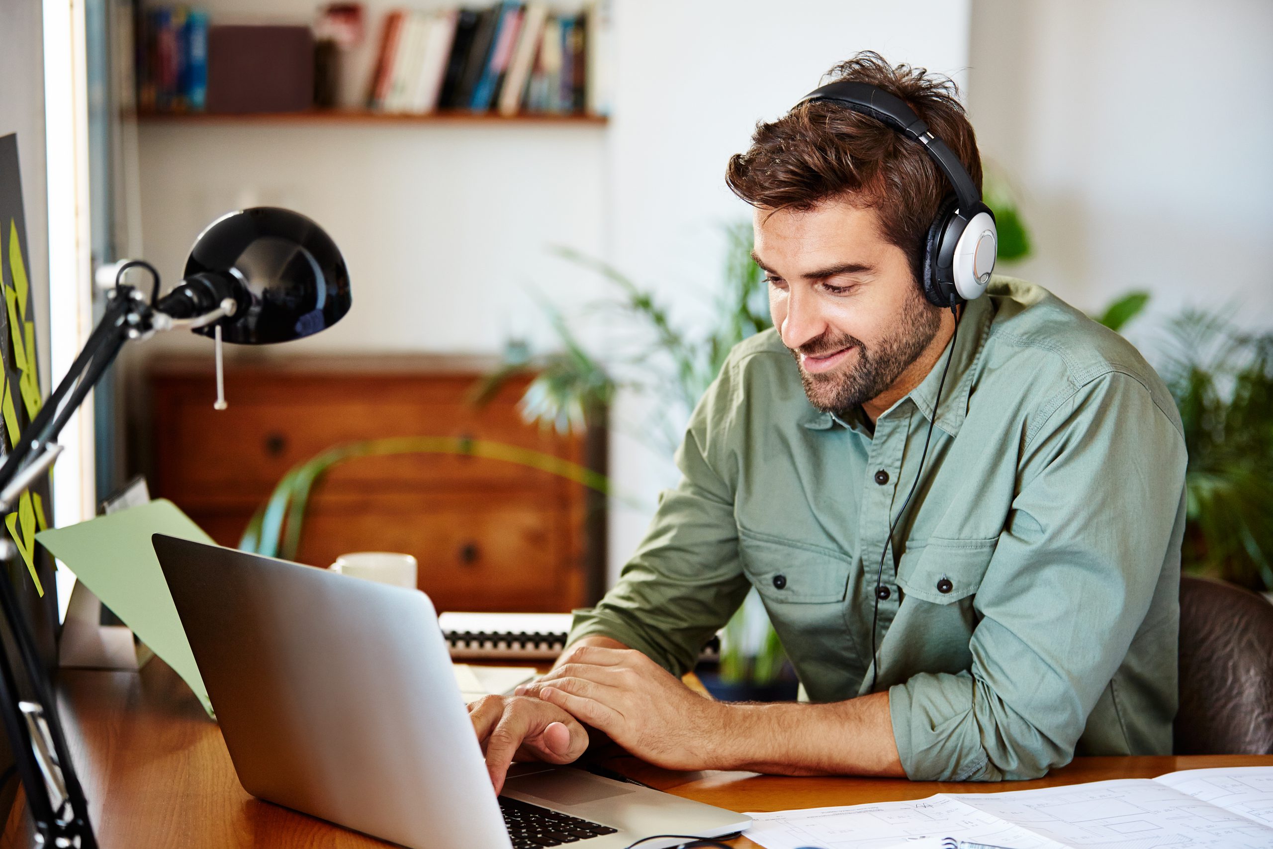 man working remotely with laptop and headphones