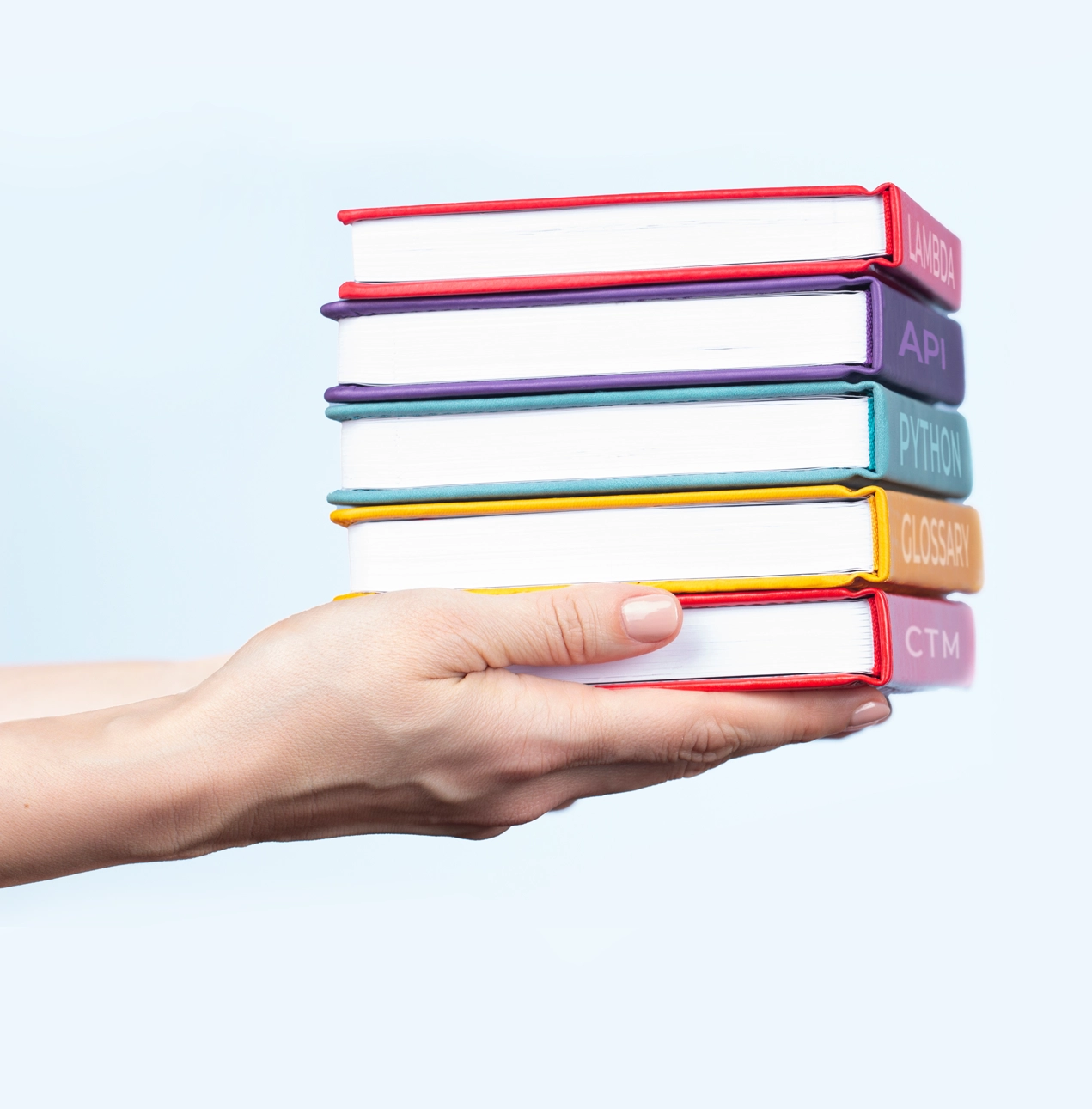 a person's hands holding a stack of text books on the topics of API, Lambda, glossary, and CallTrackingMetrics