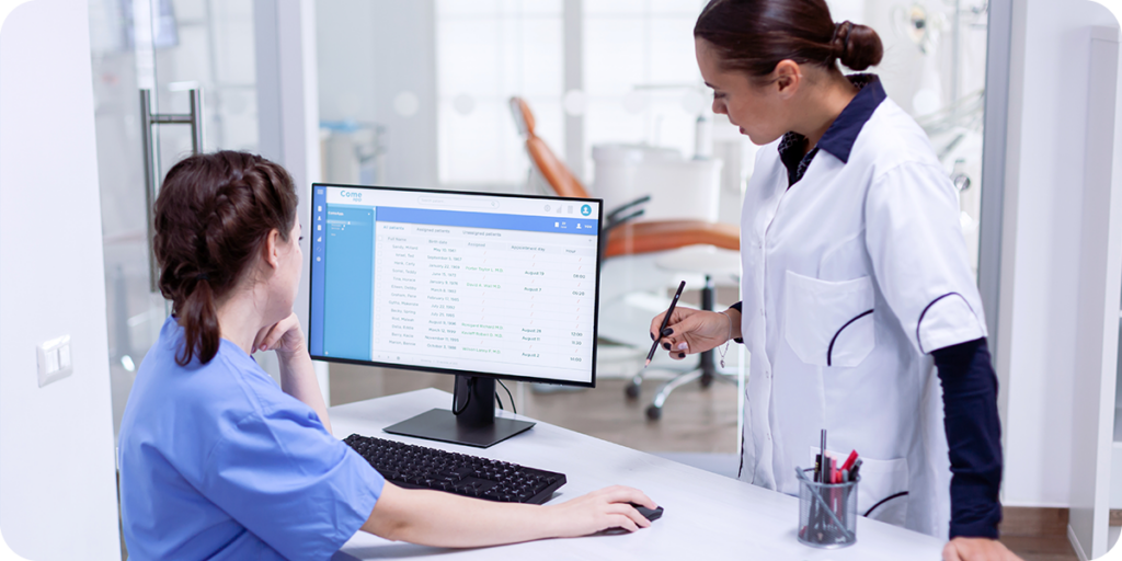 Image of two women looking at a desktop computer in a dentist's office. 